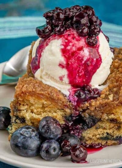 slice of blueberry buckle topped with ice cream and blueberry sauce