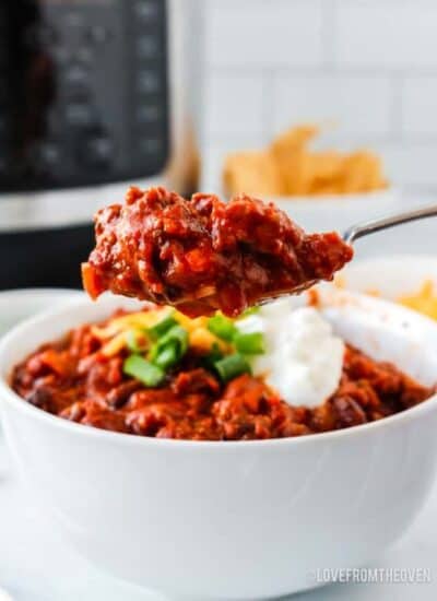 spoonful of beef chili in front of a bowl of chili