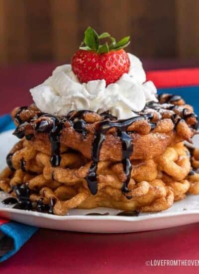 a stack of funnel cakes topped with whipped cream