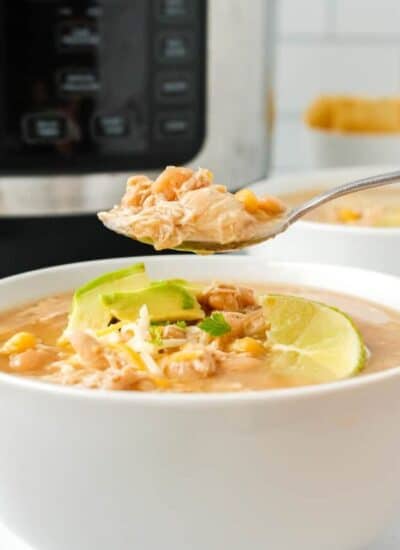 A bowl of white bean chicken chili with a spoonful being held over it