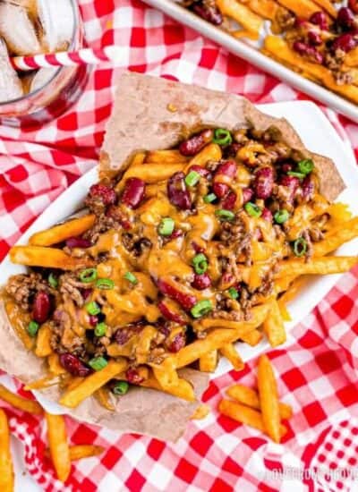 a basket of chili cheese fries on a red and white tablecloth