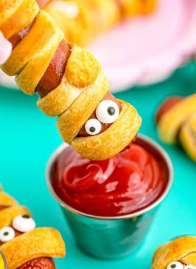 a mummy hotdog being dipped in ketchup