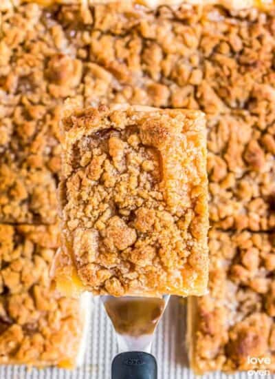 a slice of apple slab pie lifted up by a serving spatula