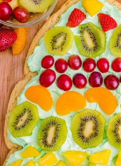 A Christmas tree fruit pizza on a wooden cutting board