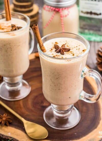 Two glasses of Coquito on a wooden slab.