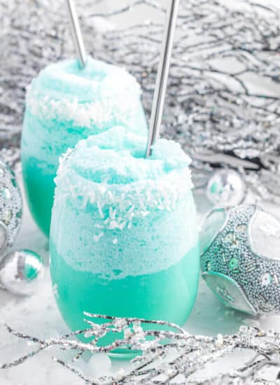 Two blue jack frost cocktails with silver straws.