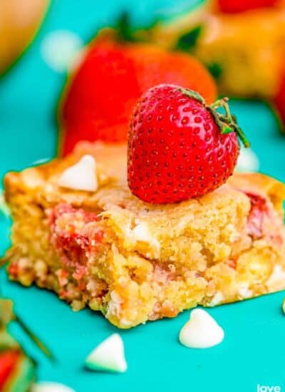 a strawberry blondie on a turquoise background topped with a strawberry