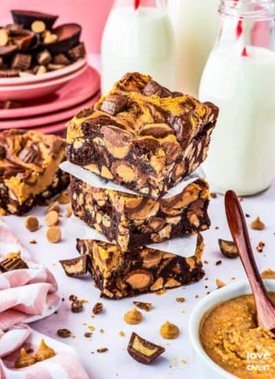 A stack of chocolate peanut butter brownies with milk bottles behind it.