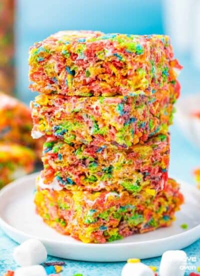 A stack of Fruity Pebbles Treats on a white plate with a blue background.