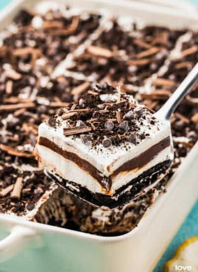 A slice of chocolate lush being taking out of a white pan.