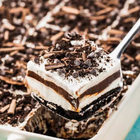 A slice of chocolate lush being taking out of a white pan.