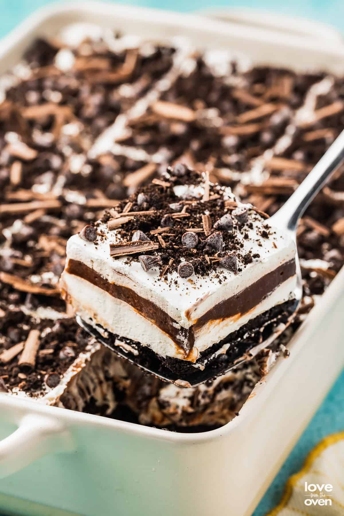 A slice of chocolate lush being taking out of a white pan.