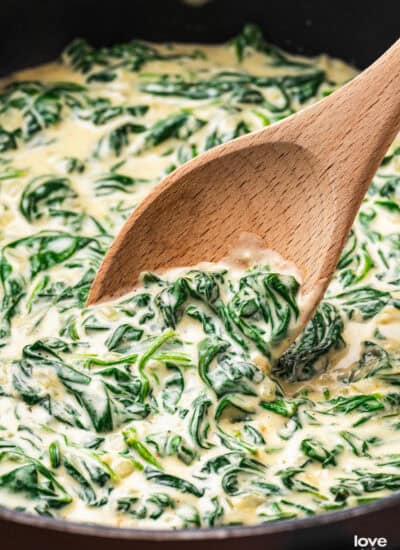 Creamed spinach in a pan with a wooden spoon