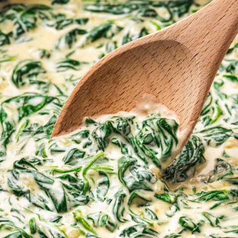 Creamed spinach in a pan with a wooden spoon