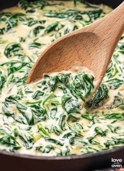 Creamed spinach in a pan with a wooden spoon