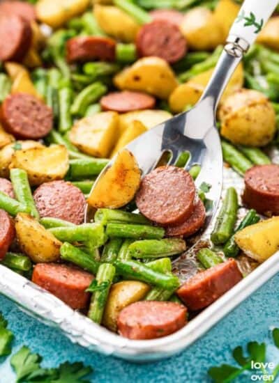 A sheet pan with smoked sausage, potatoes and green beans.