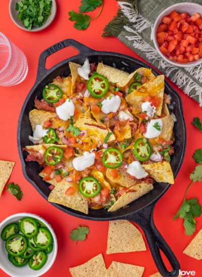 A cast iron skillet with pulled pork nachos in it