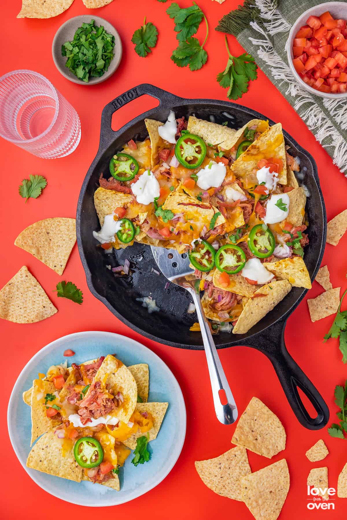 a pan of pork nachos with a serving on a plate