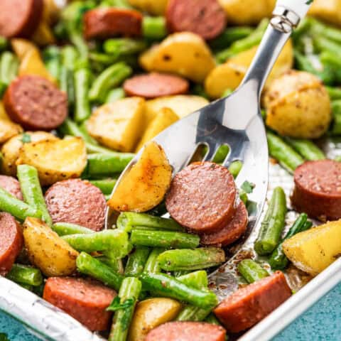 A sheet pan with smoked sausage, potatoes and green beans.