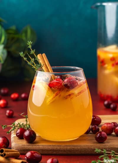 A glass of apple cider sangria with a blue background