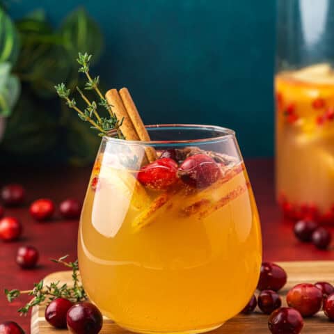 A glass of apple cider sangria with a blue background