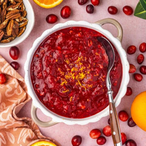 A bowl of cranberry orange relish surrounded by ingredients.