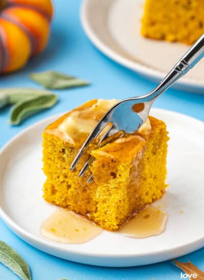 A fork cutting into a piece of pumpkin cornbread with butter on top